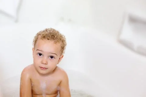 Cute two year old boy taking a relaxing bath with foam Stock Photos