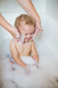 Cute two year old boy taking a relaxing bath with foam Stock Photos