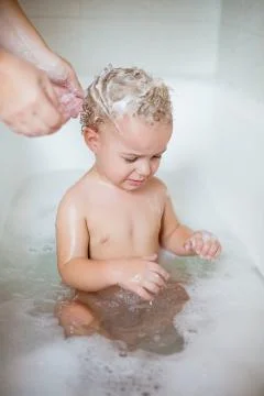 Cute two year old boy taking a relaxing bath with foam Stock Photos