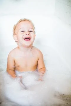 Cute two year old boy taking a relaxing bath with foam Stock Photos