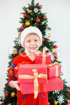 Cute white kid wearing red santa hat and holding many present boxes Stock Photos