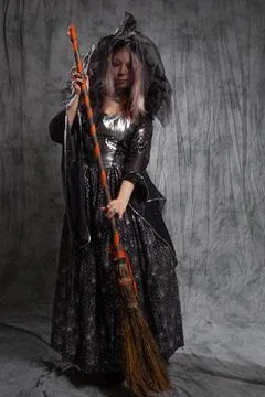Cute witch with a broom, preparing to fly to the sabbath. Stock Photos