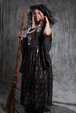 Cute witch with a broom, preparing to fly to the sabbath. Stock Photos