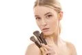 The cute woman with cosmetic brushes on the white background Photo