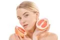 The cute woman holding a grapefruit on the white background Photo