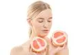 The cute woman holding a grapefruit on the white background Photo