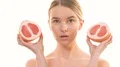 The cute woman holding two halves of a grapefruit on the white background 4k or 4k+ Resolution