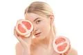 The cute woman holding two halves of a grapefruit on the white background Photo