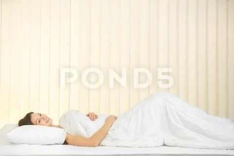 The cute woman lay on the bed and smile Stock Photos
