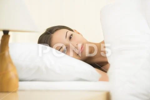 The cute woman lay on the bed with white linens Stock Photos