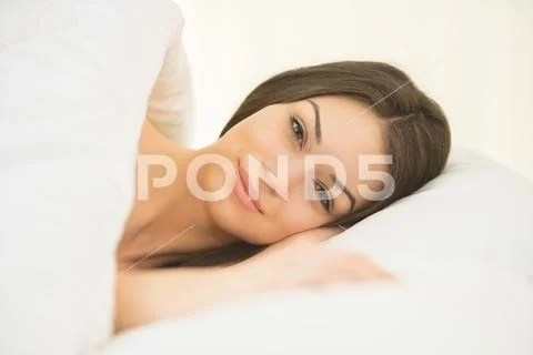 The cute woman lay in the white linens Stock Photos
