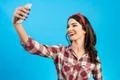 The cute woman makes a selfie on the blue background Photo