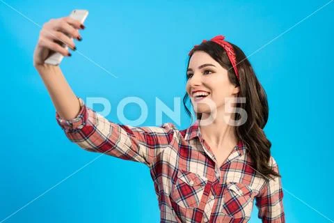 The cute woman makes a selfie on the blue background Stock Photos