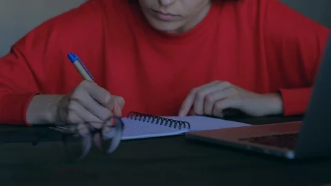 Cute woman overwrites in notepad information from the laptop. Stock Footage 112849448
