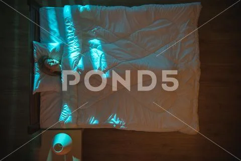 The cute woman sleeping on the bed. Evening night time. View from above Stock Photos