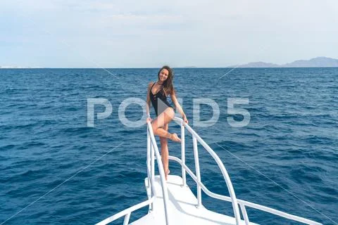 The cute woman stand in the yacht on the sea background Stock Photos