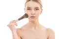 The cute woman using a cosmetic brush on the white background Photo