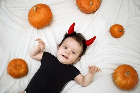 Cute year-old funny baby boy dressed as a devil horns with pumpkins the white Stock Photos
