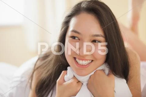 Cute young asian woman holding her duvet and smiling Stock Photos