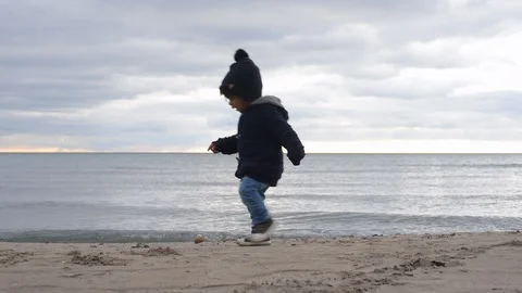 Cute young black boy picking up rock on beach Stock Footage 88934168