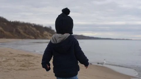 Cute young black boy picking up rock on beach Stock Footage 88955643