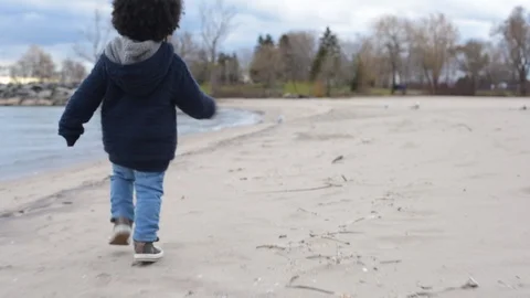 Cute young black boy running along beach by water. 库存影片 88930770