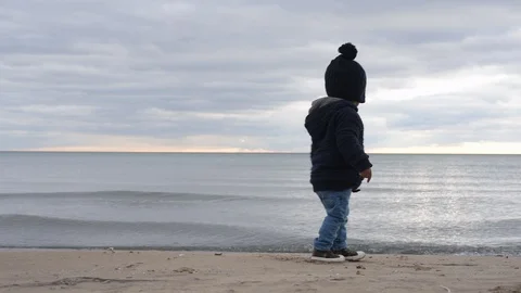 Cute young black boy throwing rock into water Stock Footage 88932849
