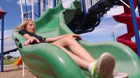 Cute young blonde sliding down green slide at playground Stock-Footage 53768149