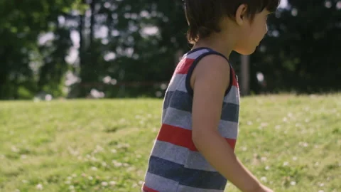 A cute young boy climbs a grass hill and plays in the park 스톡 동영상 143635529