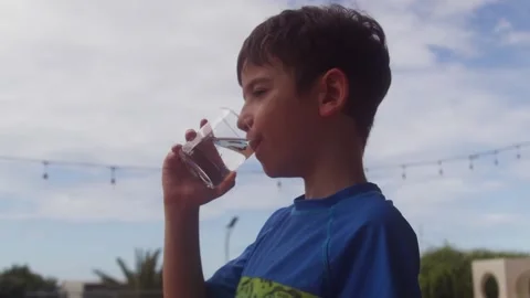 Cute young boy drinking fresh pure water from glass outdoors Vidéo 343553869