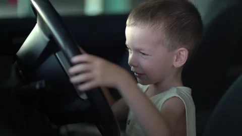 A cute young boy happily turns the steering wheel in the car Stock-Footage 342191537