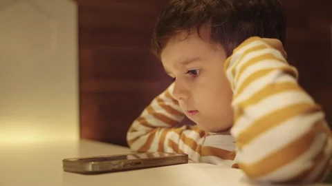 Cute Young Boy Kid Watching Cartoons on Smart Phone Stock Footage 257015813