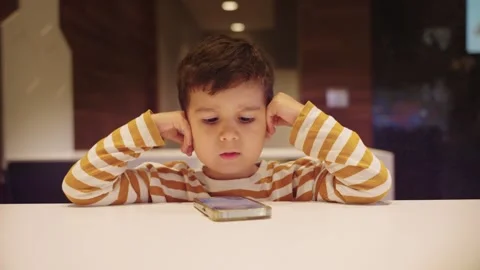 Cute Young Boy Kid Watching Cartoons on Smart Phone Video stock 257015884