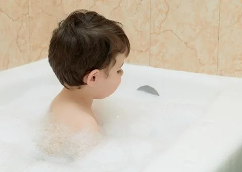 Cute young boy playing with bubbles while taking a bath Stock Photos