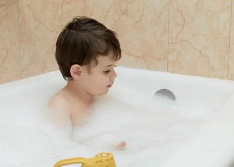 Cute young boy playing with bubbles while taking a bath Stock Photos