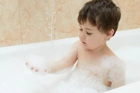 Cute young boy playing with bubbles while taking a bath Stock Photos