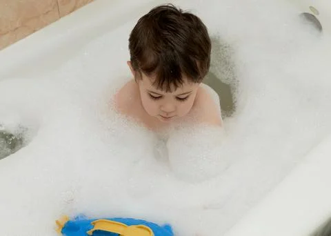 Cute young boy playing with bubbles while taking a bath Stock Photos
