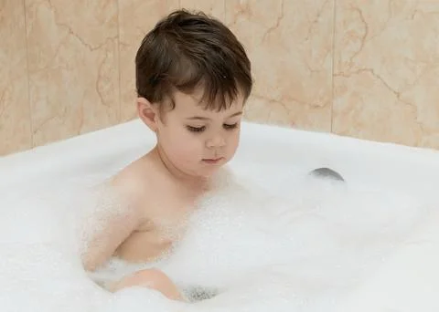 Cute young boy playing with bubbles while taking a bath Stock Photos