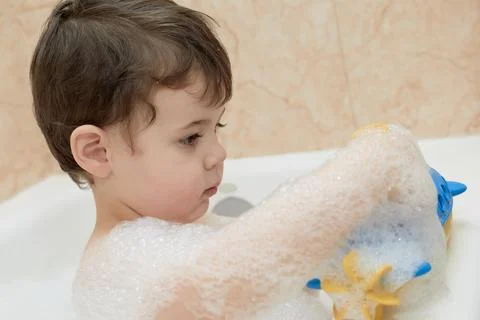 Cute young boy playing with bubbles while taking a bath Stock Photos