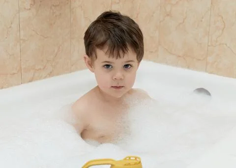 Cute young boy playing with bubbles while taking a bath Stock Photos
