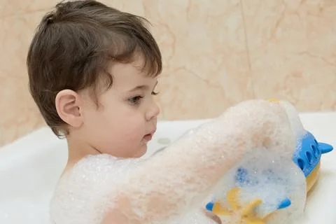 Cute young boy playing with bubbles while taking a bath Stock Photos