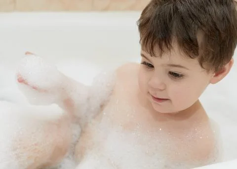 Cute young boy playing with bubbles while taking a bath Stockfoto's
