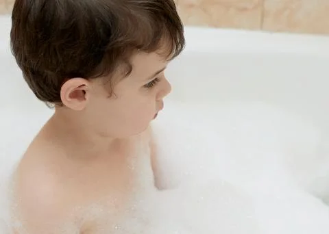 Cute young boy playing with bubbles while taking a bath Stock Photos