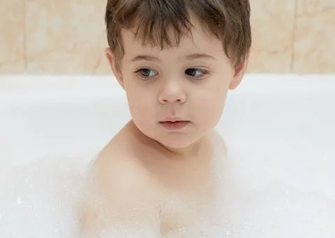 Cute young boy playing with bubbles while taking a bath Stock Photos
