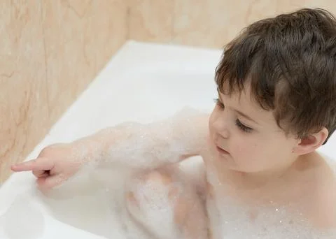 Cute young boy playing with bubbles while taking a bath Stock Photos