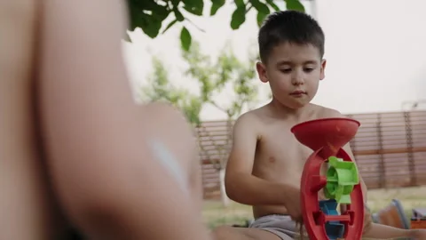 Cute young boy playing with his younger sister in the sand using sand toys and Stock Footage 250308829