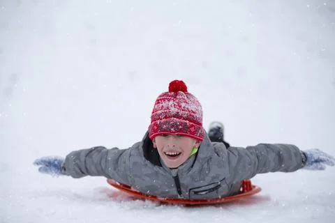 Cute young boy smiling while he is sledding Stock Photos