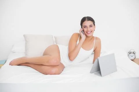 Cute young brown haired model in white pajamas making a phone call Stock Photos