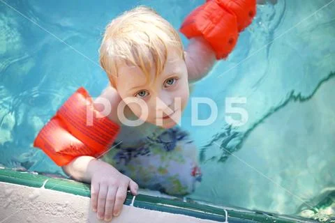 Cute Young Child with Arm Floaties in Swimming Pool Stock Photos