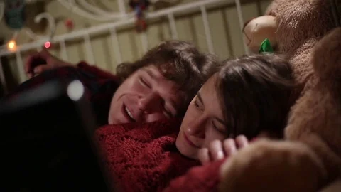 Cute Young Couple Chat in Bed While Watching Movie Video stock 72197023